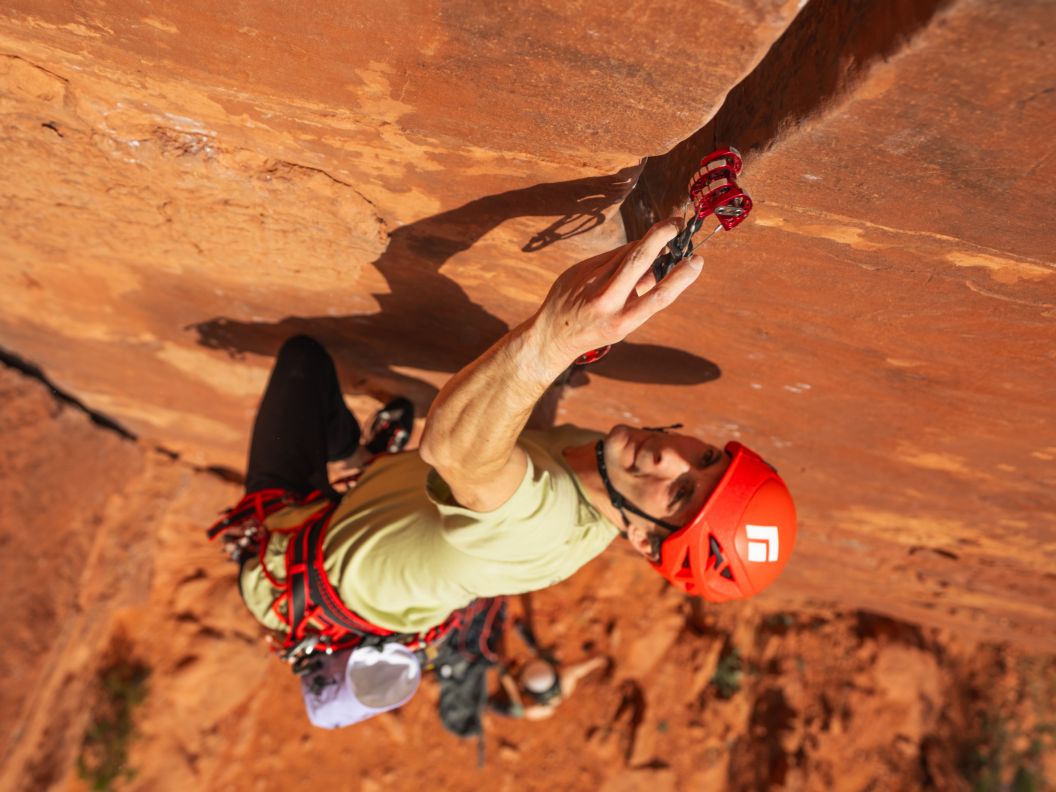 A trad climber places a red cam in a splitter crack.